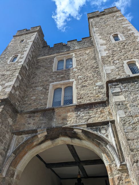 The image displays the exterior stone façade of Reigate Castle, a historic structure with a medieval appearance, featuring three visible narrow, arched windows with decorative stone lintels, and a la
